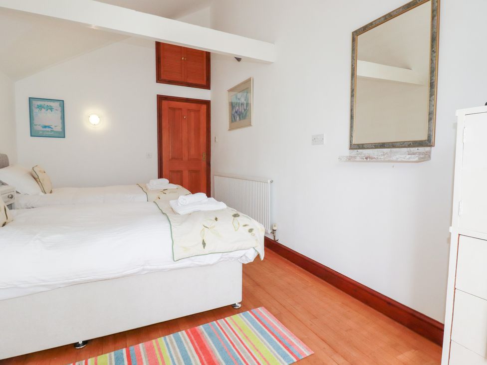 A bedroom with two beds and a mirror at Rosemaddon in Crantock