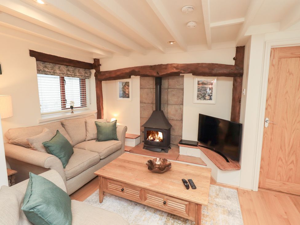 A living room with a fireplace and sofa at Jasmine Cottage in Thornthwaite
