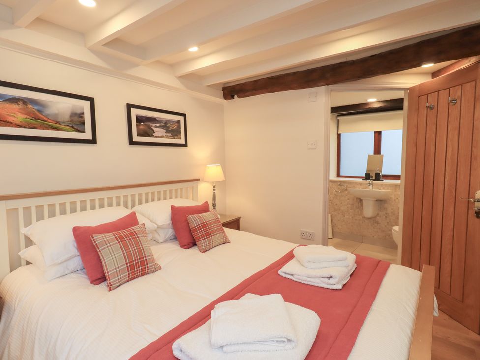 A bedroom with a bed and attached bathroom at Jasmine Cottage Thornthwaite