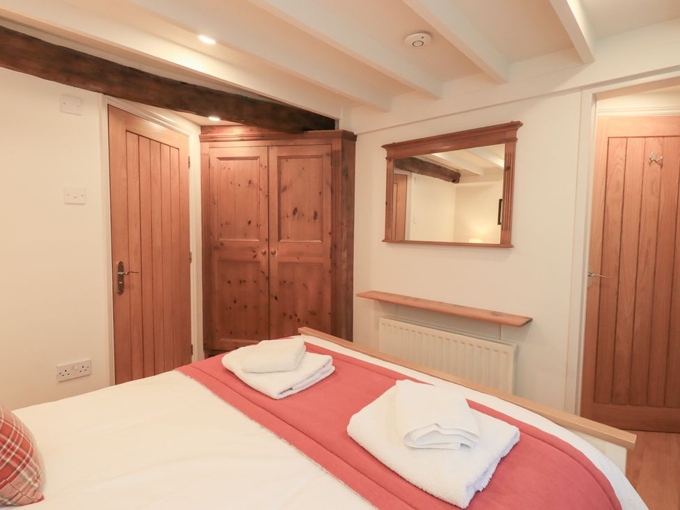 A bedroom with a bed and wardrobe at Jasmine Cottage in Thornthwaite