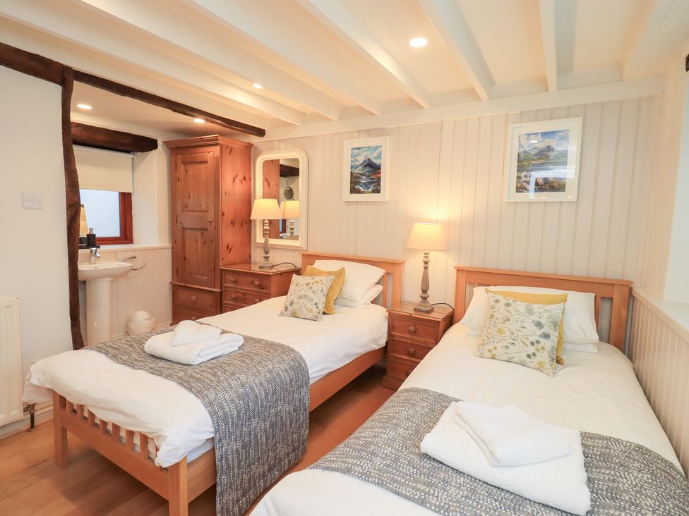 A bedroom with two beds and a bedside table at Jasmine Cottage in Thornthwaite