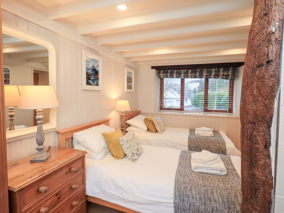 A bedroom with two beds and a lamp at Jasmine Cottage in Thornthwaite