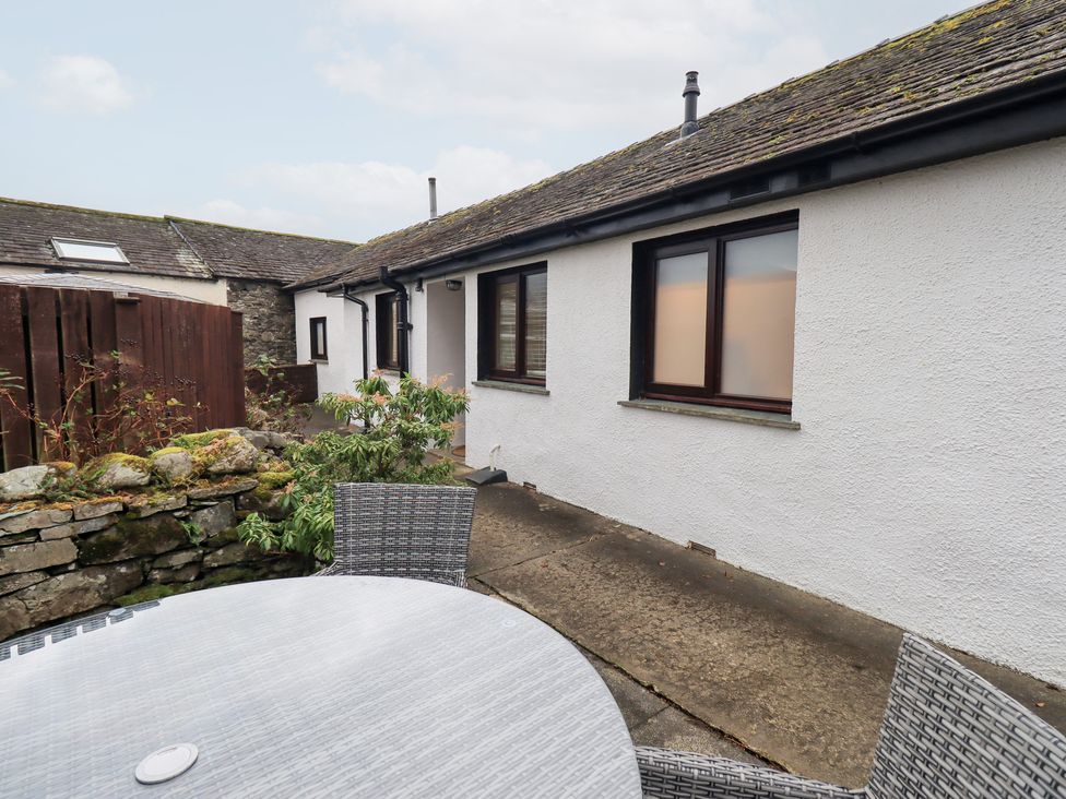 An outdoor patio area with a table and chairs at Jasmine Cottage in Thornthwaite
