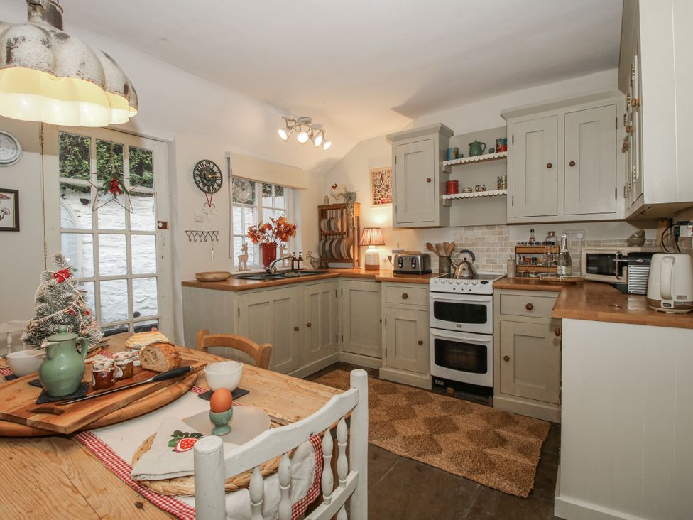 A kitchen with cabinets, stove, and dining table at 8 Welsh Street in Bishops Castle