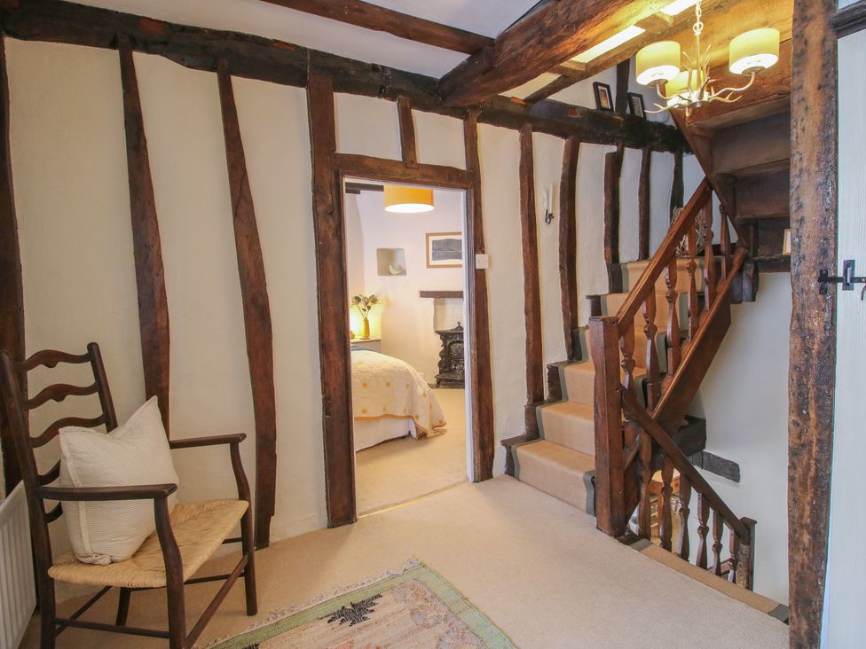 A hallway with a staircase and a chair at 8 Welsh Street Bishop's Castle