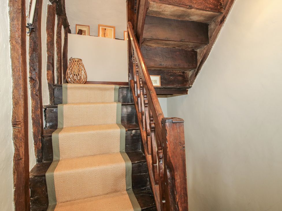 A staircase with a runner rug and decorative vase at 8 Welsh Street in Bishop's Castle