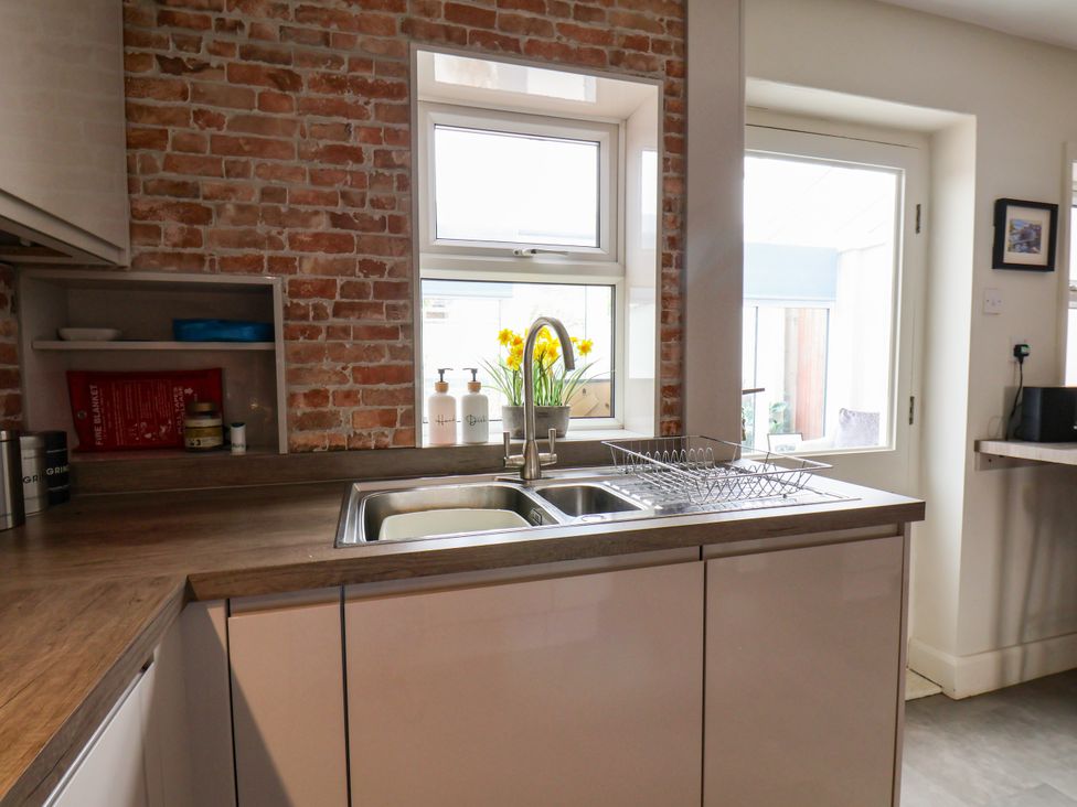 A kitchen with a sink, dish rack, and brick wall at 7 St. Germains Lane