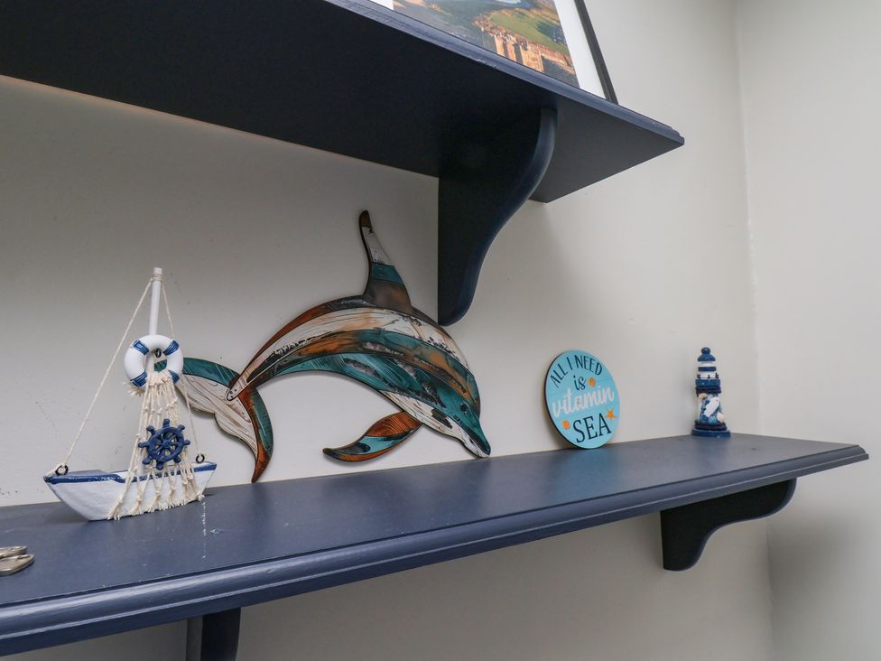 A shelf with decorative items including a dolphin, boat, lighthouse, and a phrase sign at 7 St. Germains Lane
