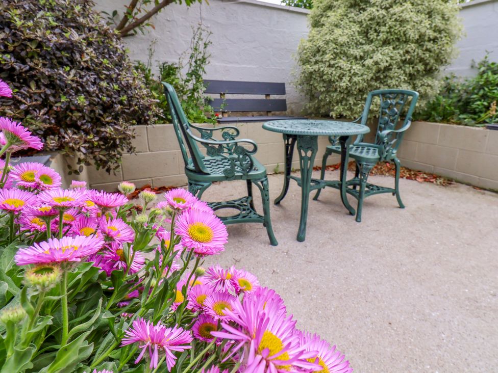 A garden with a table and chairs surrounded by flowers at 7 St. Germains Lane