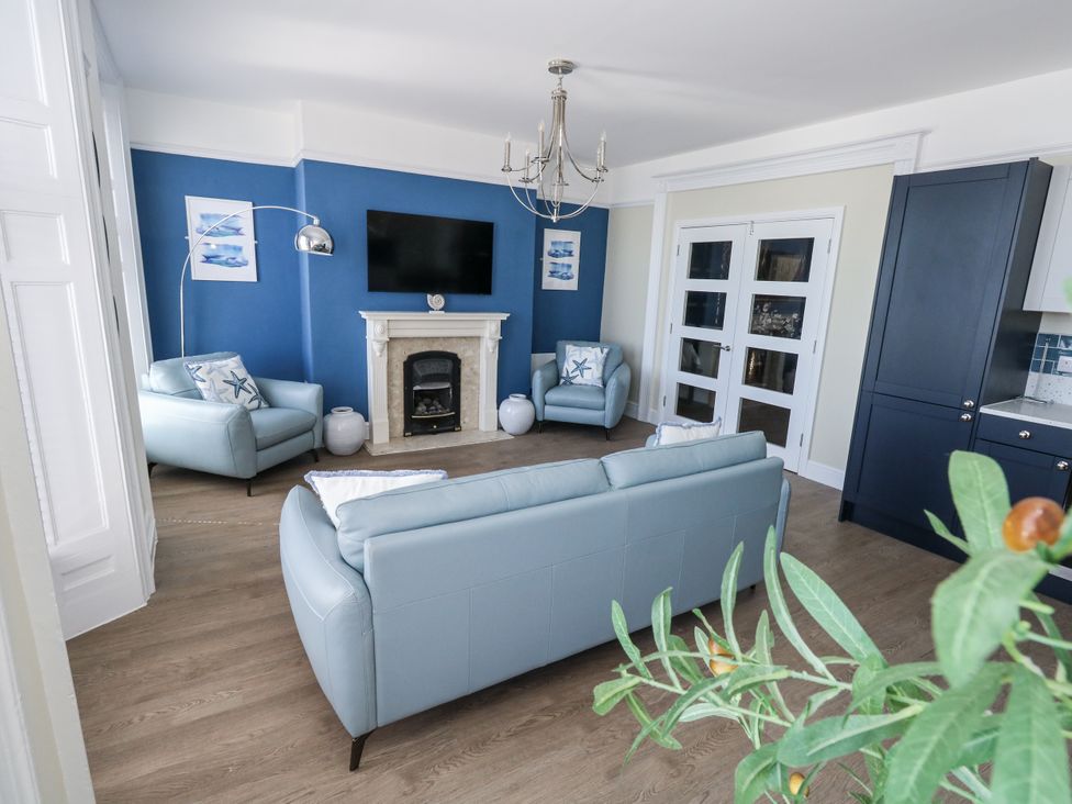 A living room with a television and two armchairs at Apartment 1 in Weymouth