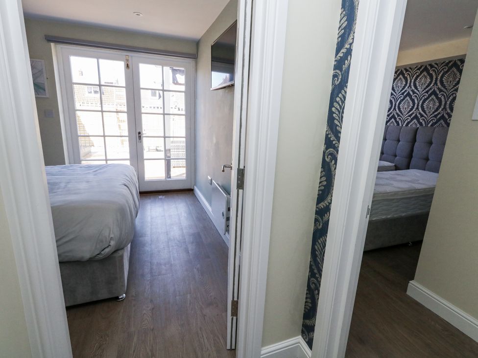 A bedroom with two beds and a balcony door at Apartment 1 in Weymouth