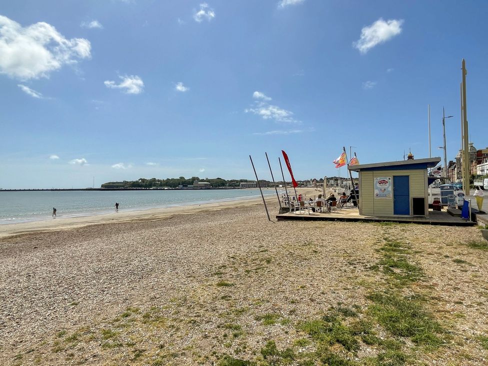A beach with a café and people walking at Apartment 1 Weymouth