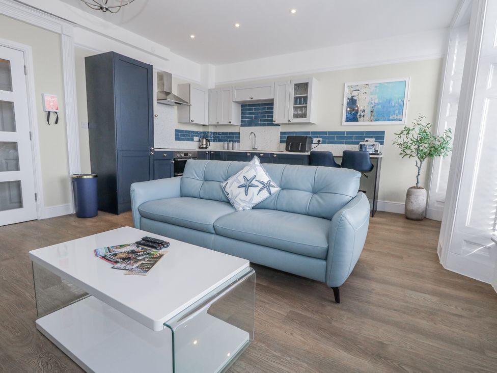 A living room with a blue sofa and coffee table at Vista Mare 1 in Weymouth