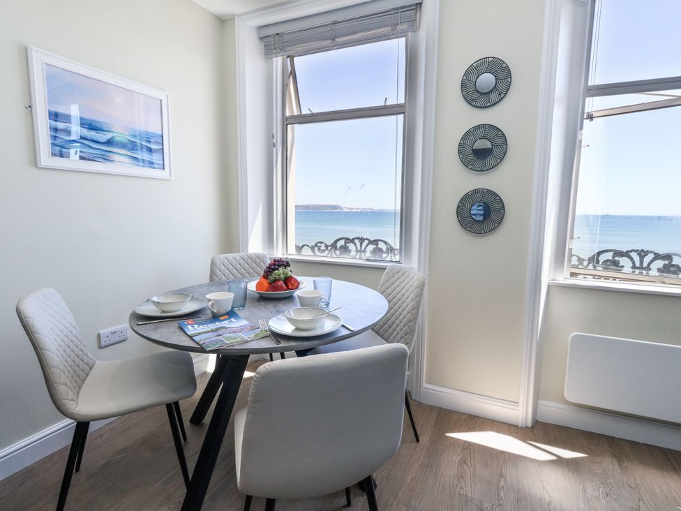A dining room with a table and chairs overlooking the sea at Apartment 2 in Weymouth