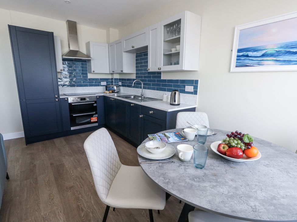 A kitchen with blue cabinets and a dining table at Apartment 2 Weymouth