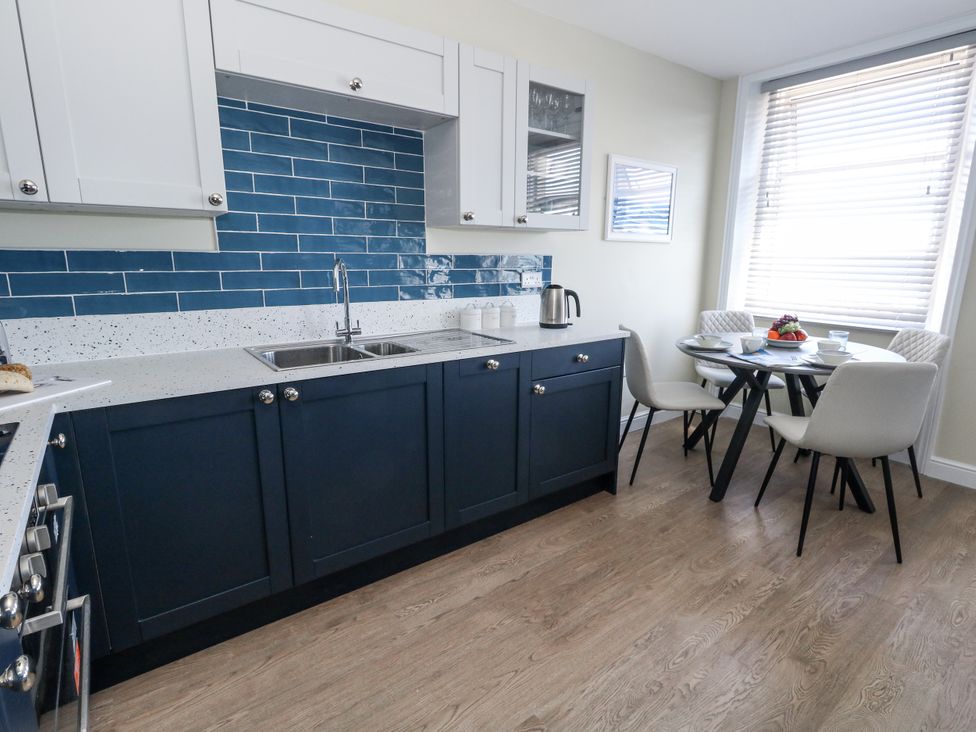 A kitchen with cabinets and a dining table at Apartment 2 in Weymouth