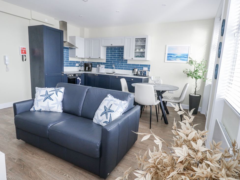 A living room with a sofa and dining area at Vista Mare 2 Weymouth