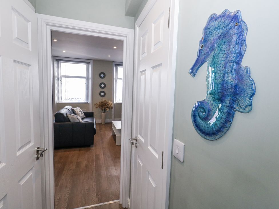 A hallway view with a seahorse decoration and a living room in sight at Vista Mare 2 Weymouth
