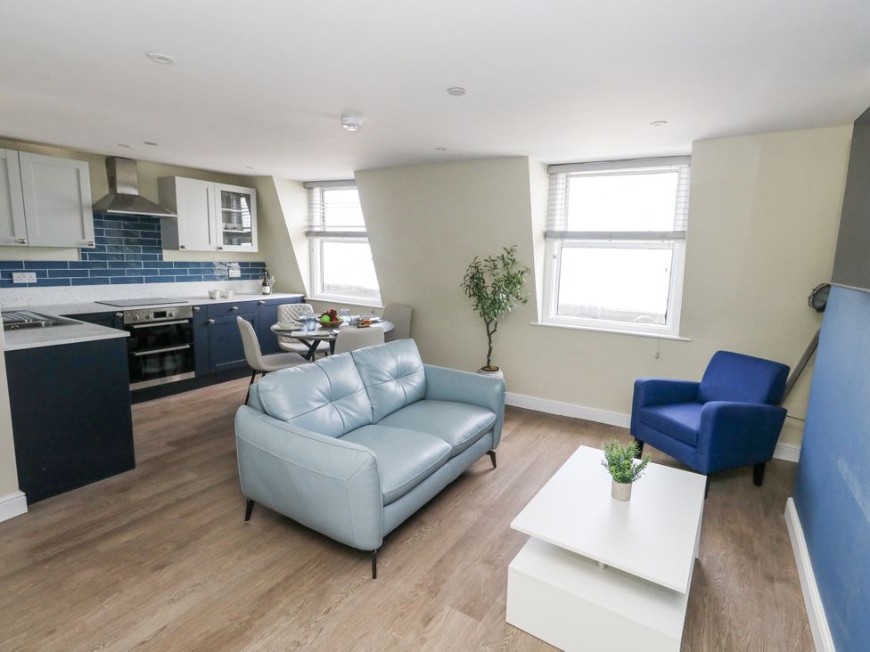A living room with a sofa and kitchen area at Apartment 3 in Weymouth