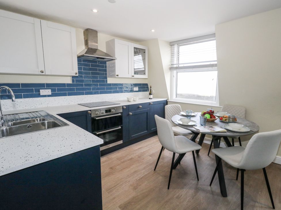 A kitchen with a sink, stove, and dining table at Apartment 3 in Weymouth