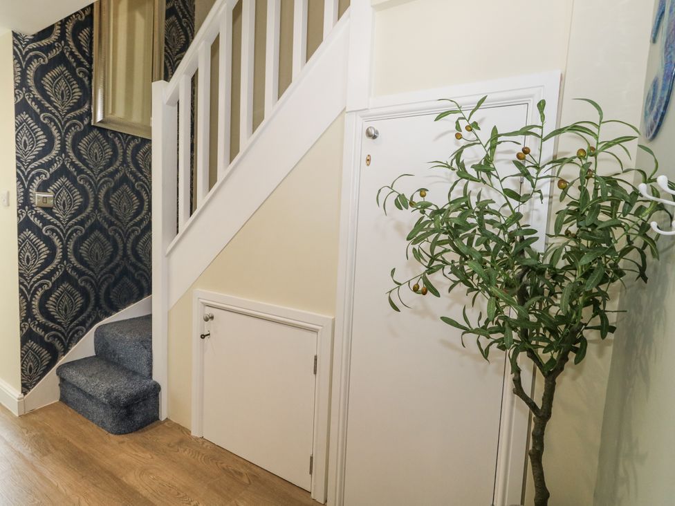 A hallway with a staircase and a plant at Apartment 3 Weymouth