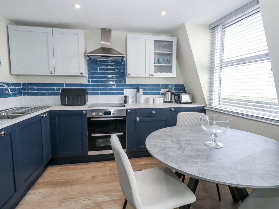 A kitchen with blue cabinets and a round table at Vista Mare 3 Weymouth