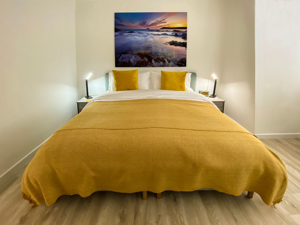 A bedroom with a bed and wall art at Sandwood Studios in Crantock