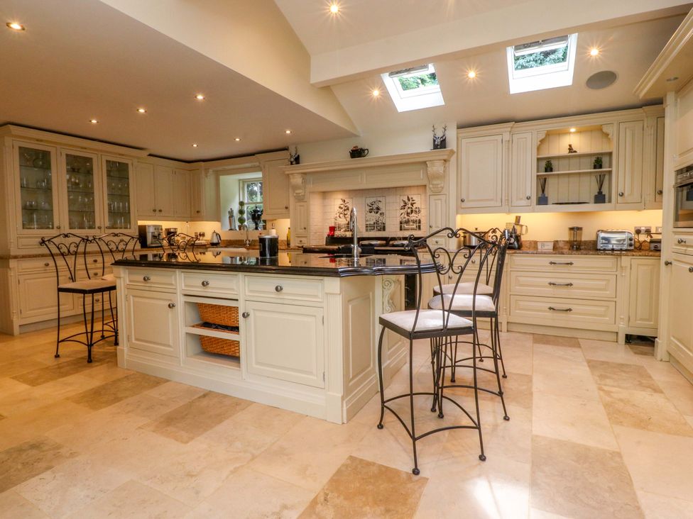 A kitchen with a central island and bar stools at Laithe House in Burnley