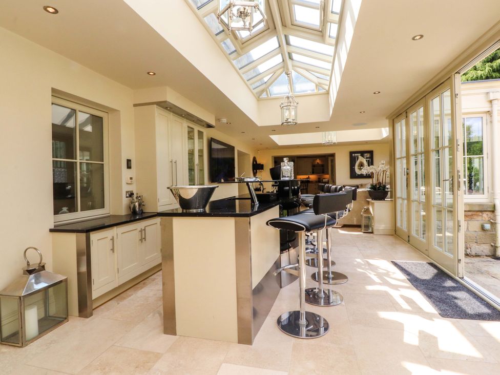 A kitchen with a central island and bar stools at Laithe House in Burnley