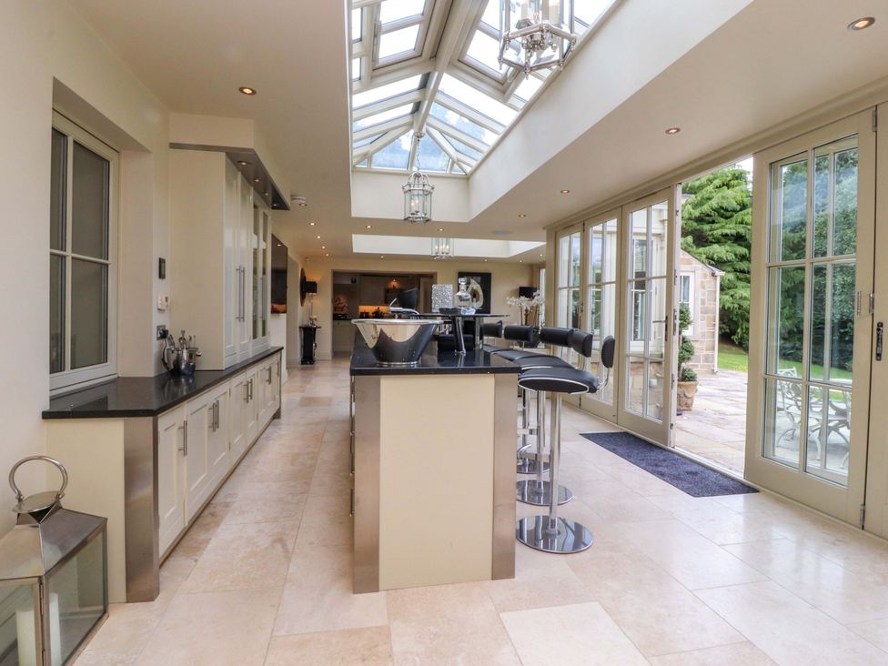 A kitchen with a central island and bar stools at Laithe House in Burnley