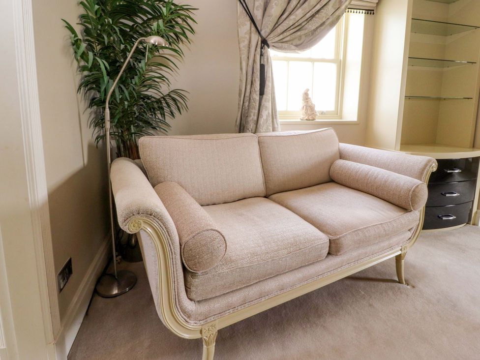 A sofa with a floor lamp and plant in a living room at Laithe House in Burnley