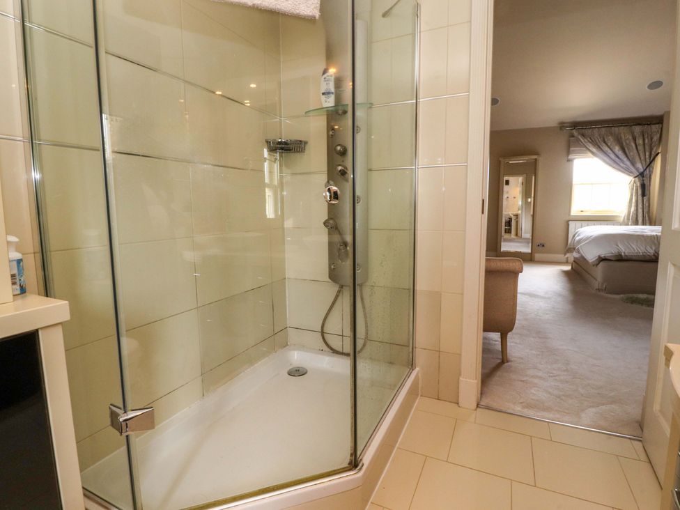 A bathroom with a shower and mirror at Laithe House in Burnley