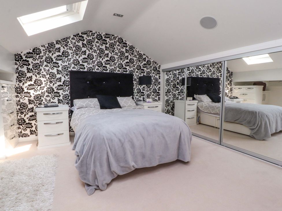 A bedroom with a bed and mirrored furniture at Laithe House in Burnley