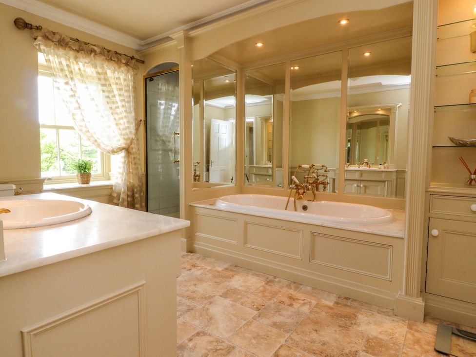 A bathroom with a bathtub, sink, and shower at Laithe House in Burnley