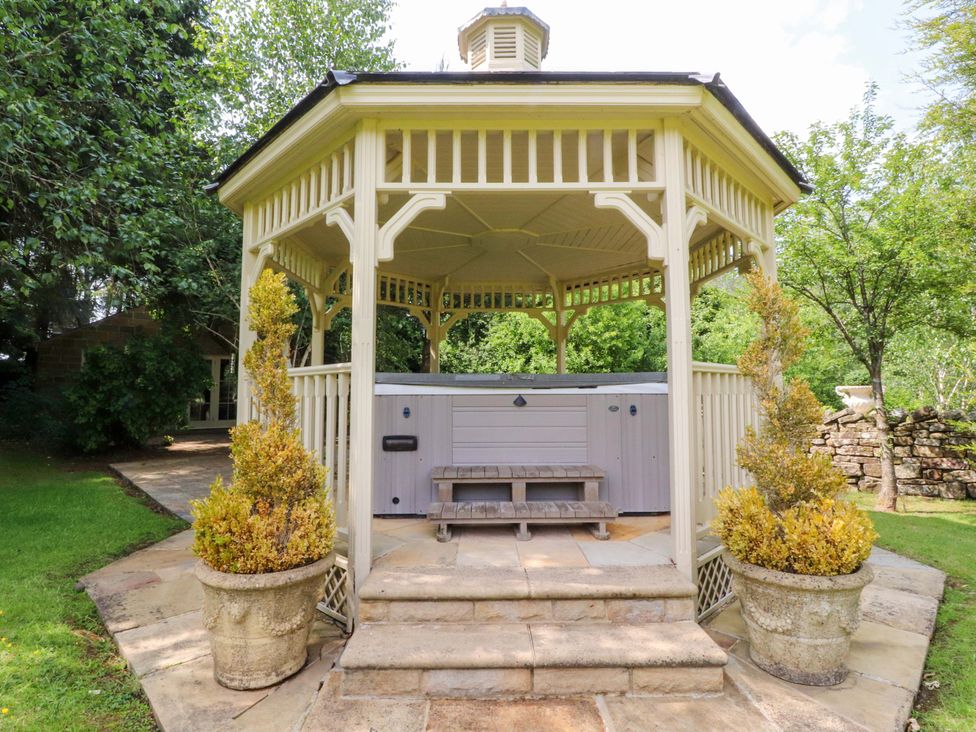 A gazebo with a hot tub and planters at Laithe House in Burnley
