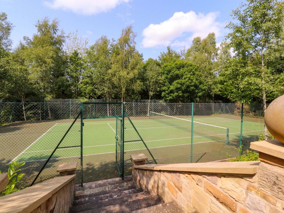 A tennis court surrounded by trees at Laithe House Burnley
