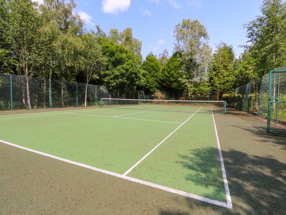 A tennis court surrounded by trees at Laithe House in Burnley