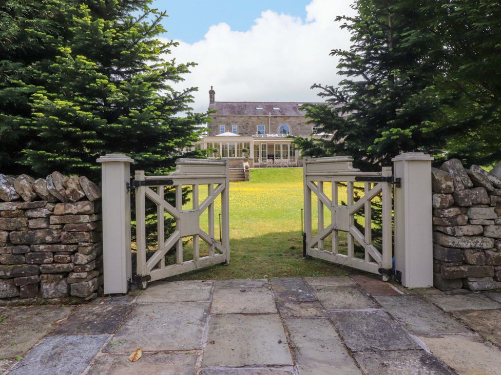 A garden with a gate and house in the background at Laithe House Burnley