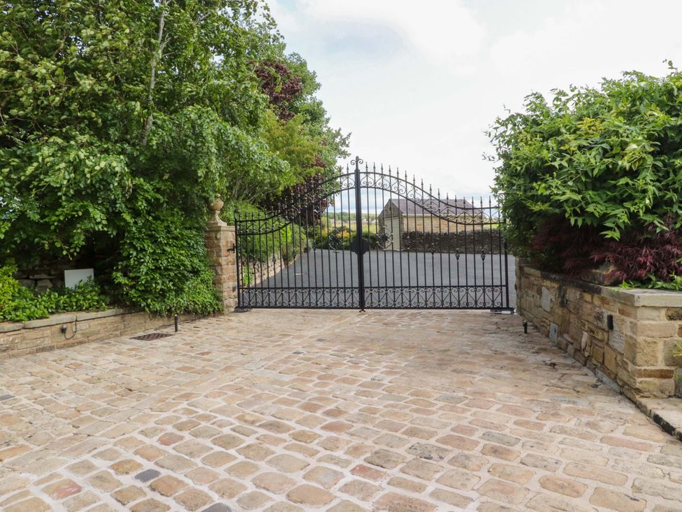 A gated entrance with a stone wall and trees at Laithe House in Burnley