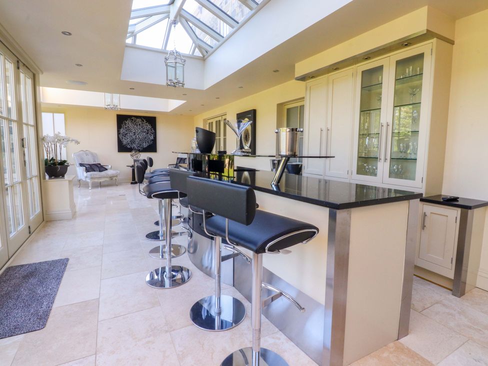 A kitchen with a bar counter and stools at Laithe House in Cliviger