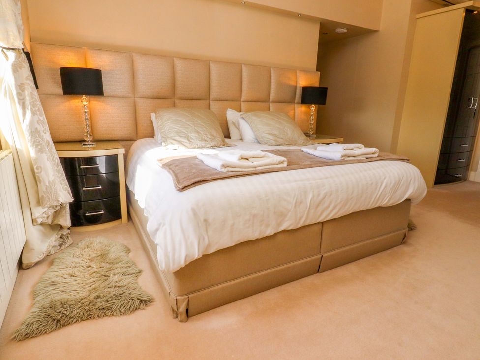 A bedroom with a large bed and nightstand at Laithe House in Cliviger