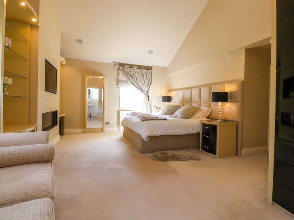 A bedroom with a bed, lamp, mirror and television at Laithe House Cliviger