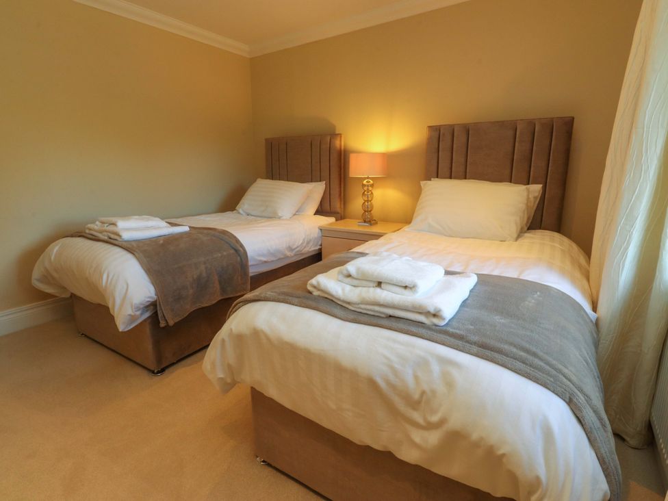 A bedroom with two beds and a lamp at Laithe House in Cliviger