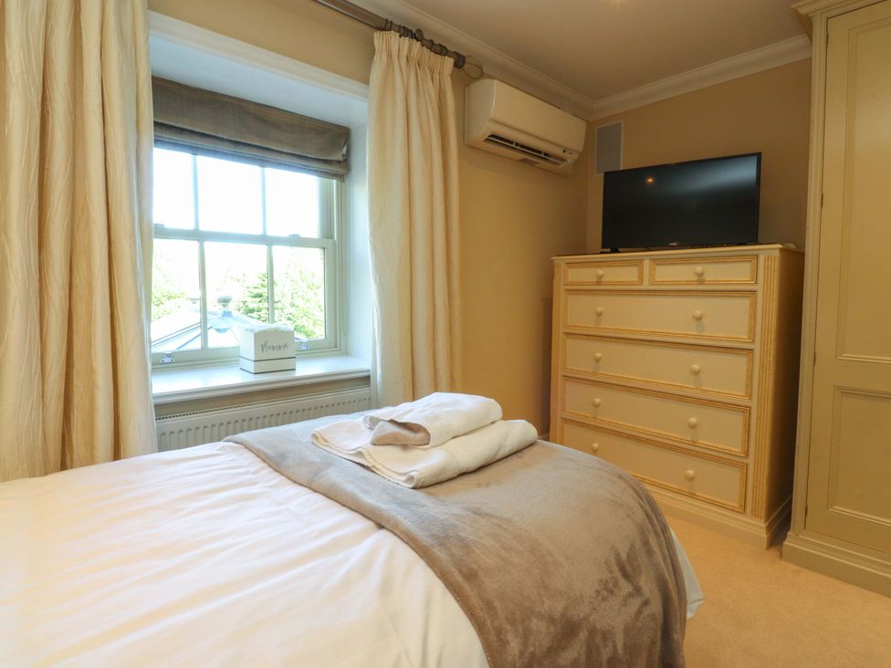 A bedroom with a bed, television, and dressing table at Laithe House in Cliviger