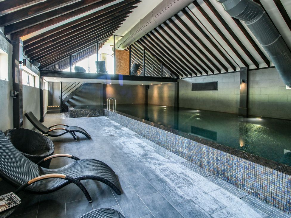 An indoor pool area with chairs and stairs at Upper Home Farm near Cardington