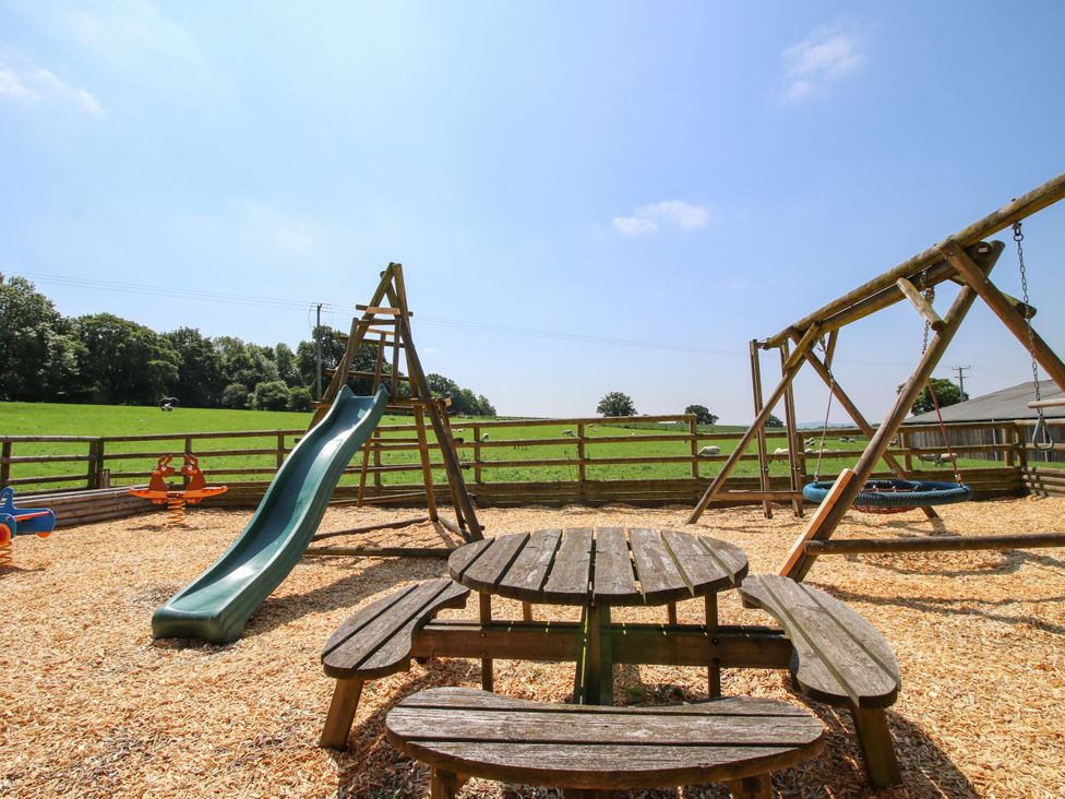 An outdoor play area with a slide, swings, and a picnic table at Upper Home Farm near Cardington