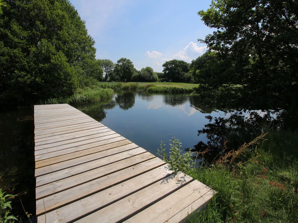 A wooden pier extending over water surrounded by trees and grass near Cardington