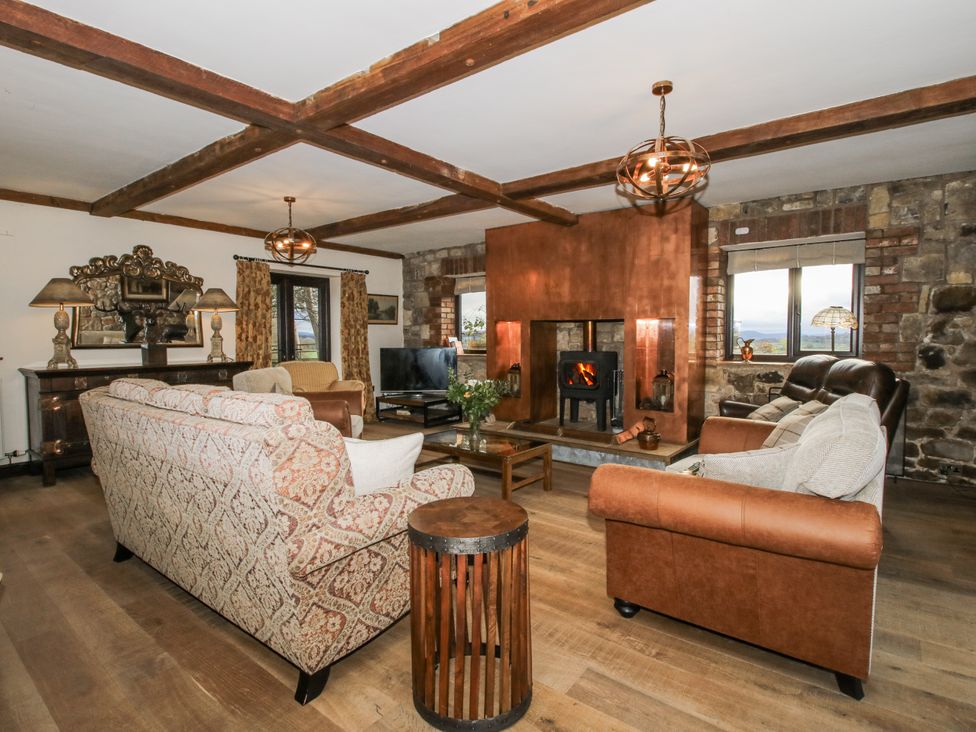 A living room with sofas, a fireplace, and a television at Upper Home Farm near Cardington