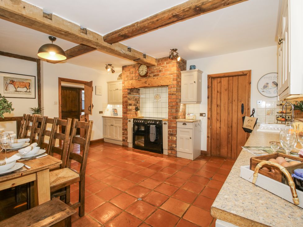 A kitchen with a brick wall and wooden dining table at Upper Home Farm near Cardington