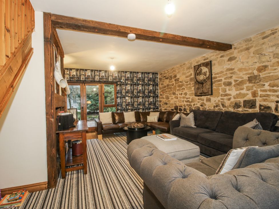 A living room with a sofa, coffee table, and staircase at Upper Home Farm near Cardington